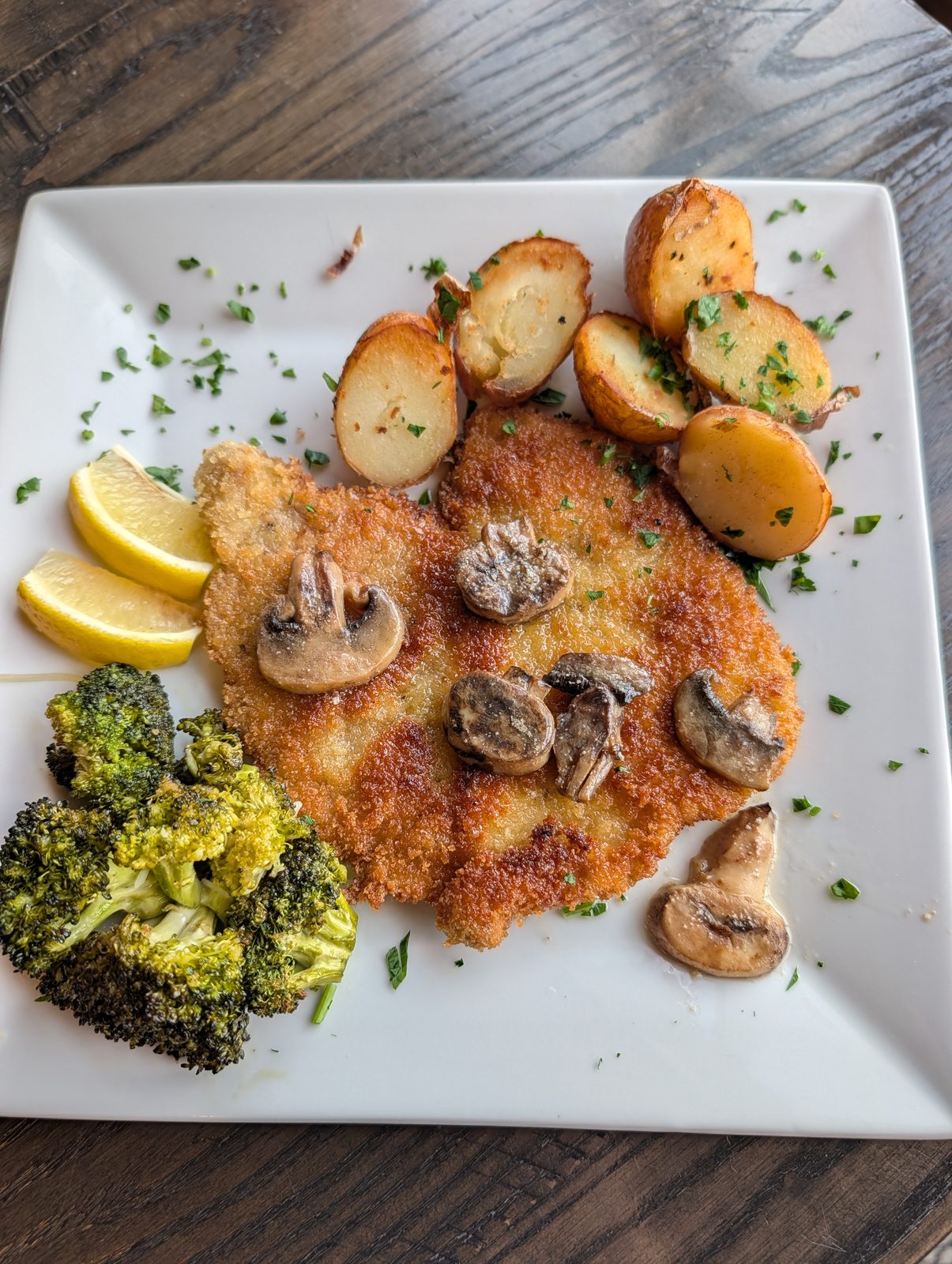 Crispy breaded cutlet topped with sautéed mushrooms, with roasted potatoes and broccoli